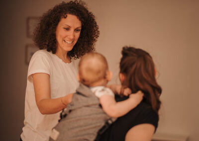 Charlène Berthon sourit en regardant un bébé et sa mère lors d'un atelier portage à Morestel