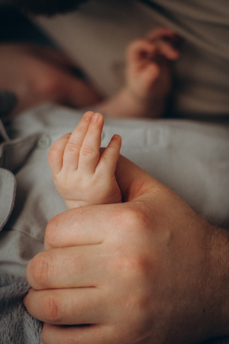 A baby's hand gripping an adult's finger.